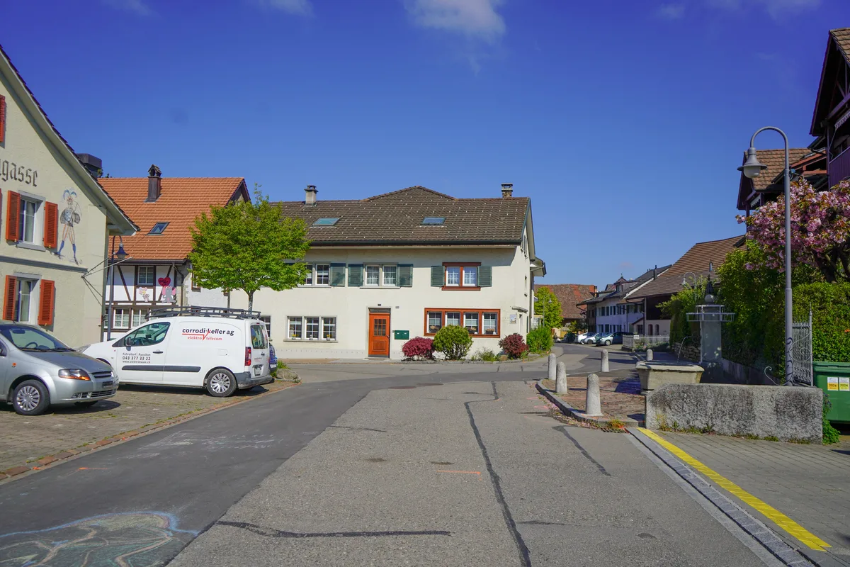 Eine Strasse mit einem Brunnen und Pollern.